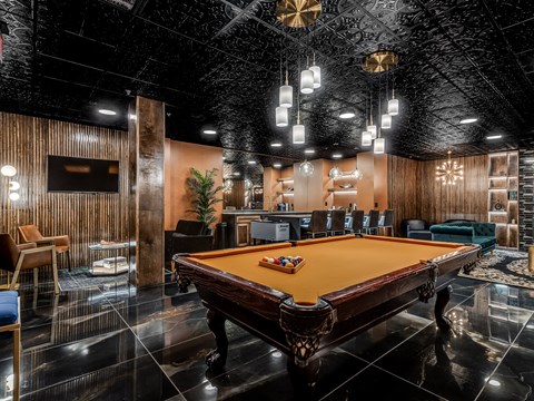 A pool table is in the middle of a room with a black ceiling.
