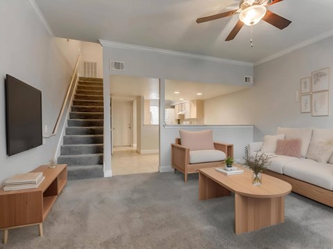 A living room with a staircase and a flat screen TV.