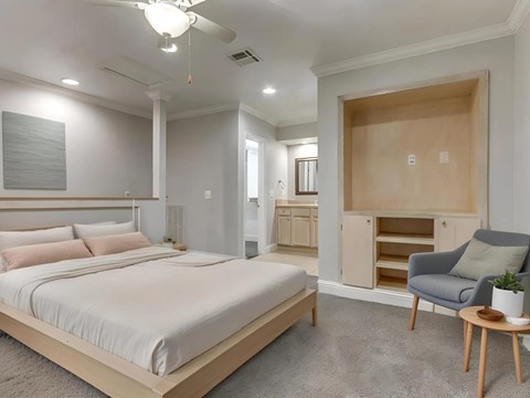 A bedroom with a large bed and a chair.