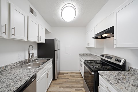 A kitchen with black appliances and white cabinets.
