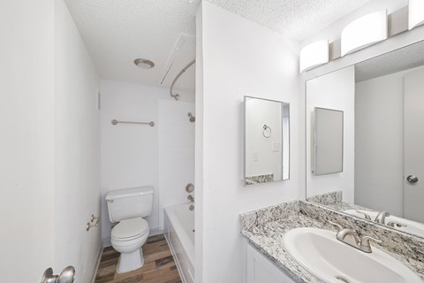 A white bathroom with a toilet, sink, and mirror.