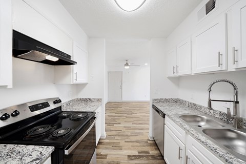 A kitchen with a black stove top oven and white cabinets.