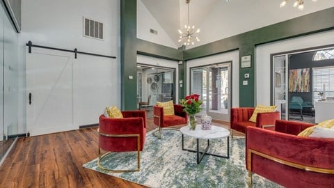 A living room with red chairs and a glass table.