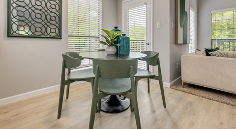 A dining room with a green table and chairs.