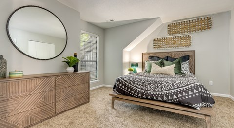 A bedroom with a bed, dresser, and mirror.