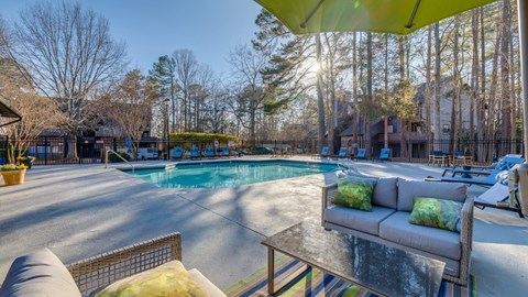 A sunny day at the poolside with a yellow umbrella providing shade.