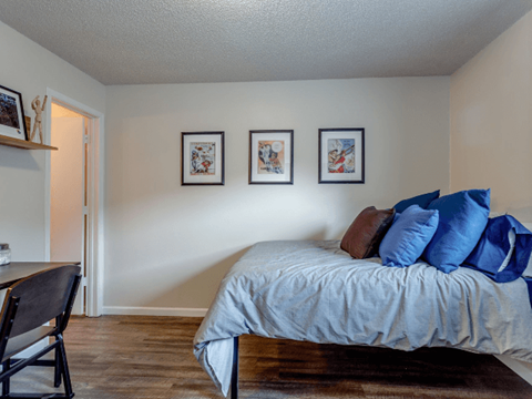 A bedroom with a bed, chair, and pictures on the wall.