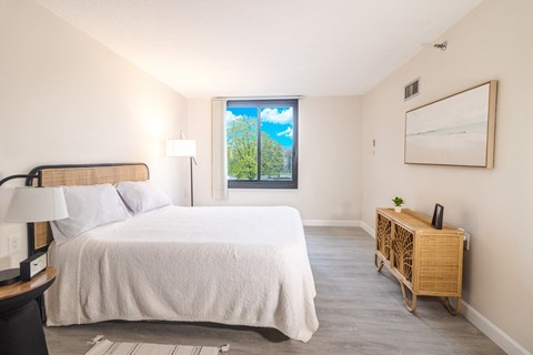 A bedroom with a large bed and a window overlooking a green landscape.