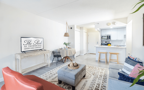 A living room with a red chair and a sign that says "The Park at Trowbridge Senior Living".