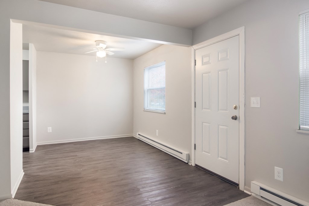 A room with a white door, a window with blinds, and a ceiling fan.