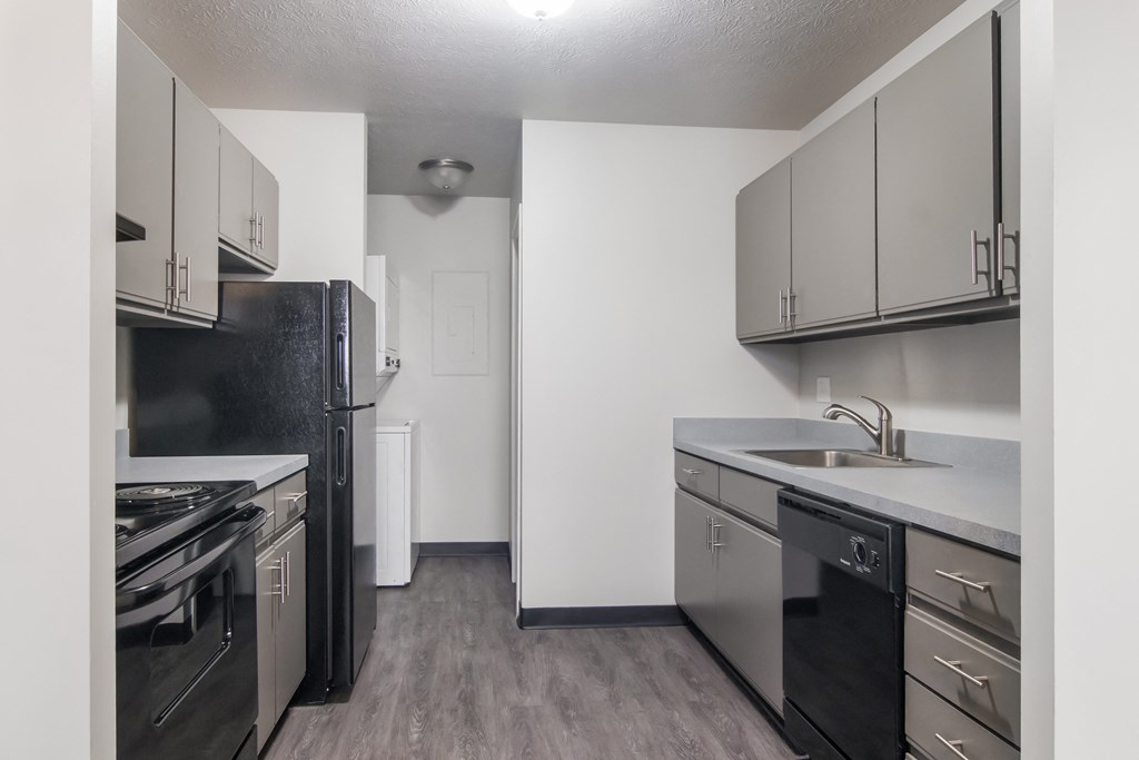 A kitchen with black appliances and white walls.