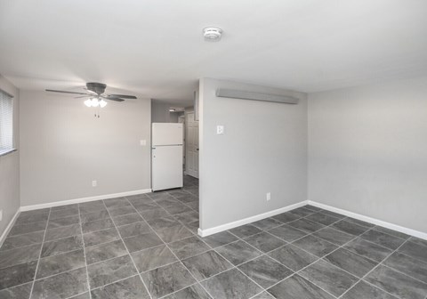 A spacious room with tile flooring and a ceiling fan.