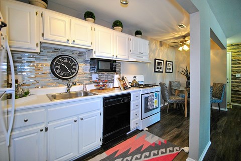 A kitchen with white cabinets and a black clock on the wall.