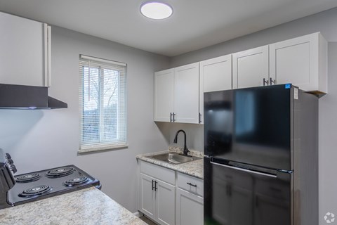 A kitchen with a stove, sink, and refrigerator.