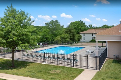 A pool surrounded by a black fence and trees.