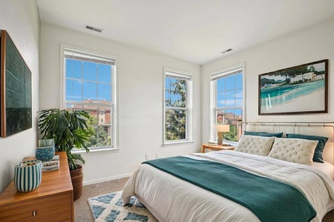 Bright bedroom with ocean artwork and teal bedding at Regents Club of Troy Apartments, Troy