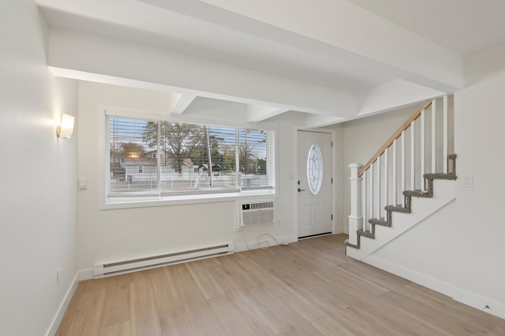 A spacious room with a staircase and a window overlooking a street.