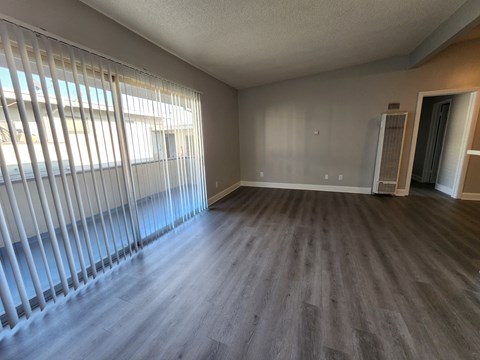 A room with wooden floors and a window with blinds.