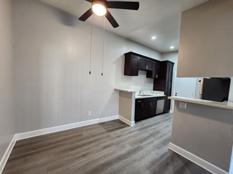 A room with a ceiling fan and a kitchen area.