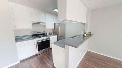 A kitchen with white cabinets and a stainless steel refrigerator.