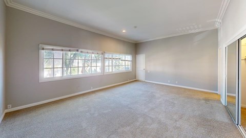 A spacious room with a large window and carpeted floor.