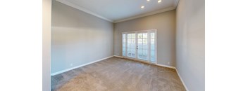 A room with a carpeted floor and a window with blinds.