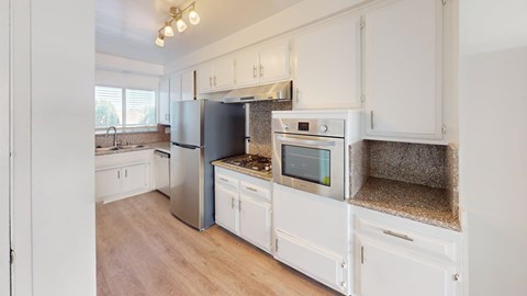 A kitchen with white cabinets and a stainless steel refrigerator.