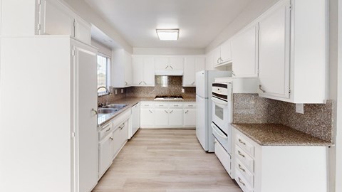 A white kitchen with wooden floors and white appliances.