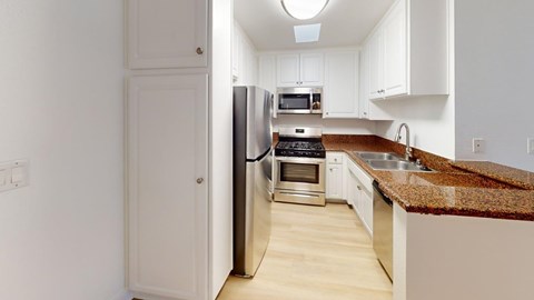 A kitchen with a granite counter top and stainless steel appliances.