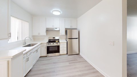 A kitchen with white cabinets and a stainless steel trash can.