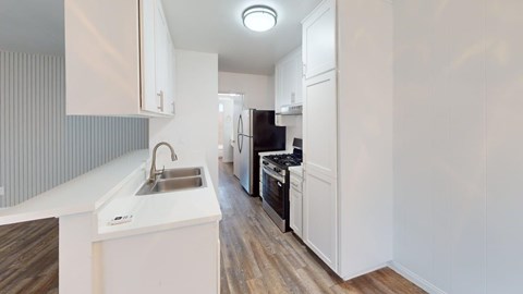 A modern kitchen with white cabinets and a wooden floor.