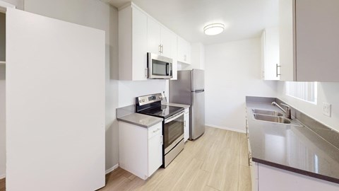 A kitchen with white cabinets and appliances.