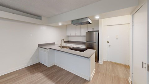 A kitchen with a refrigerator, sink, and cabinets.
