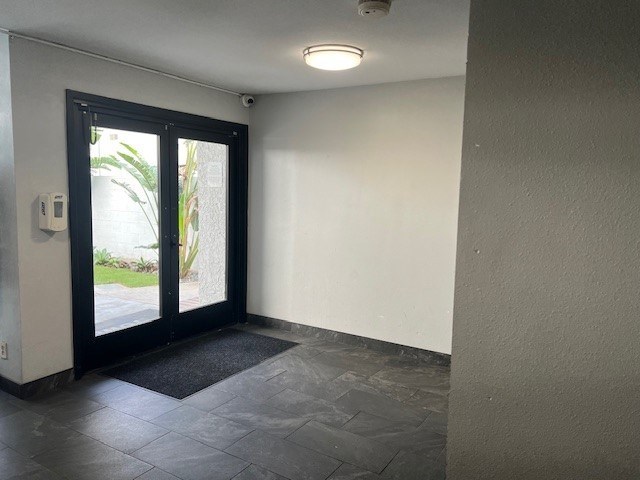 A black door with a window on the other side is open.