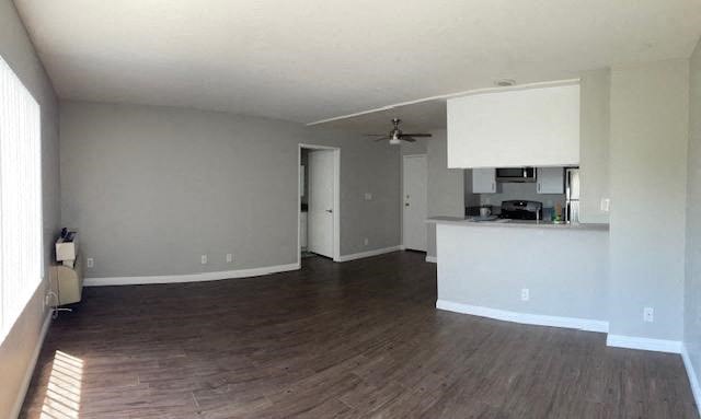 A room with a kitchenette and a ceiling fan.