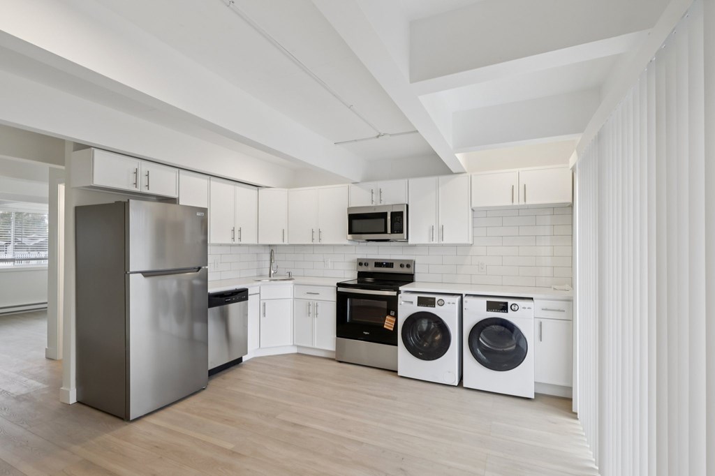 A modern kitchen with white cabinets and stainless steel appliances.