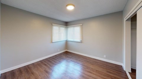 A room with wooden flooring and a window with blinds.