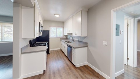 A kitchen with white cabinets and a black fridge.
