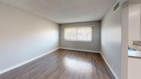 A room with wooden flooring and a window with blinds.