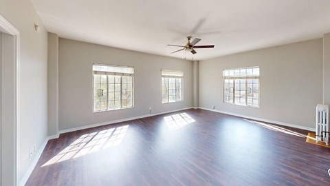 A spacious room with wooden floors and a ceiling fan.