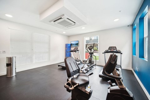 A gym with a variety of equipment including treadmills and stationary bikes.