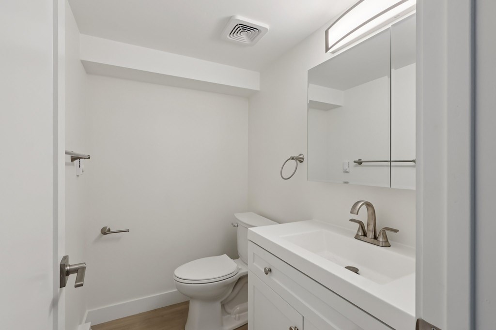 A white bathroom with a toilet, sink, and mirror.