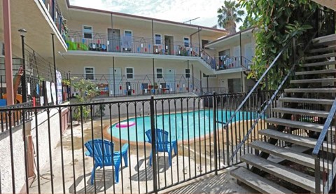 a large swimming pool with tables and chairs in front of a building