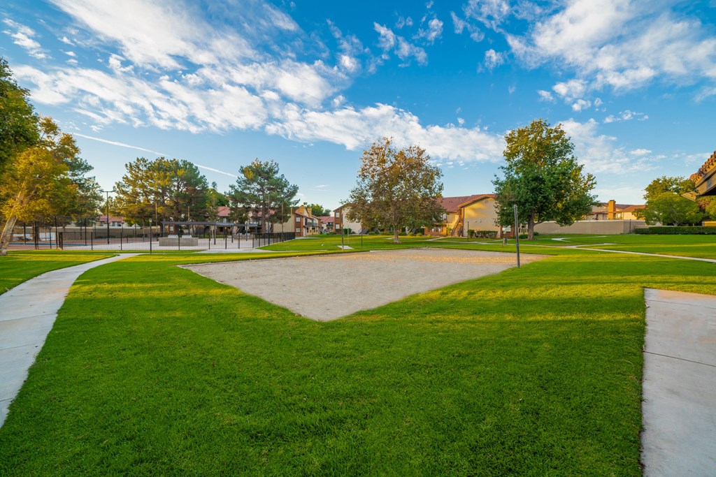a grassy area with trees and buildings in the background