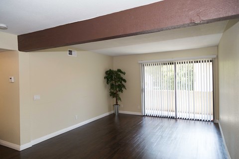 an empty living room with wood floors and a window