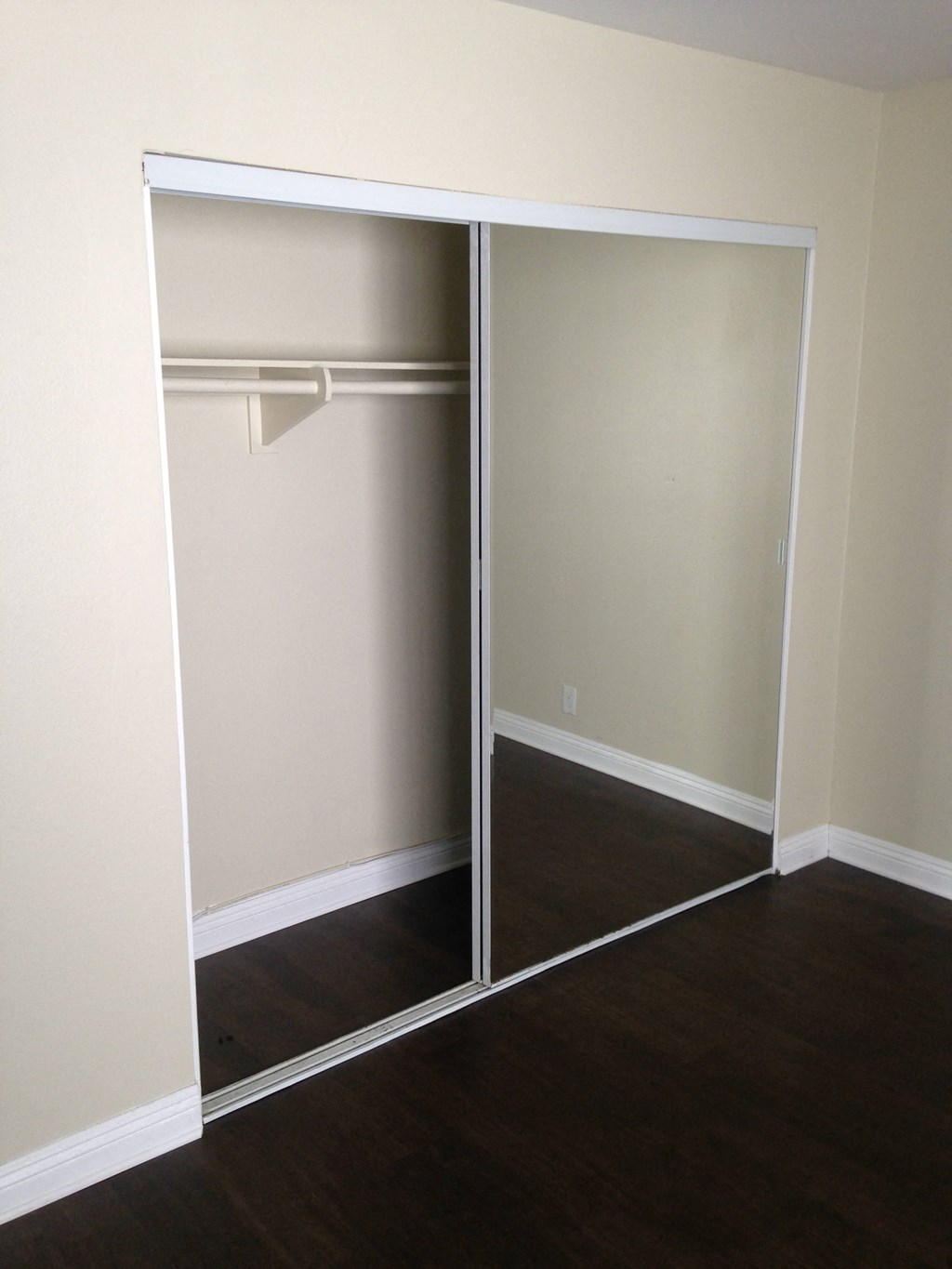 A white closet with a mirror door is open.