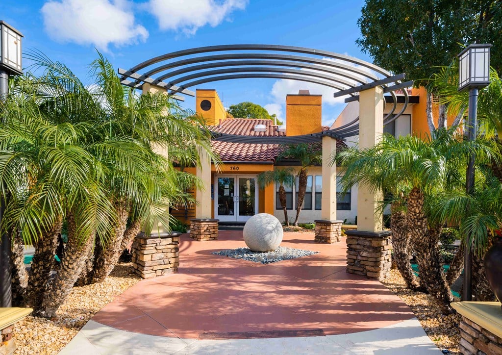 a home with palm trees and a large sphere in the middle of a walkway