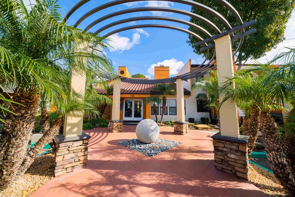 a courtyard with palm trees and a fountain in front of a house