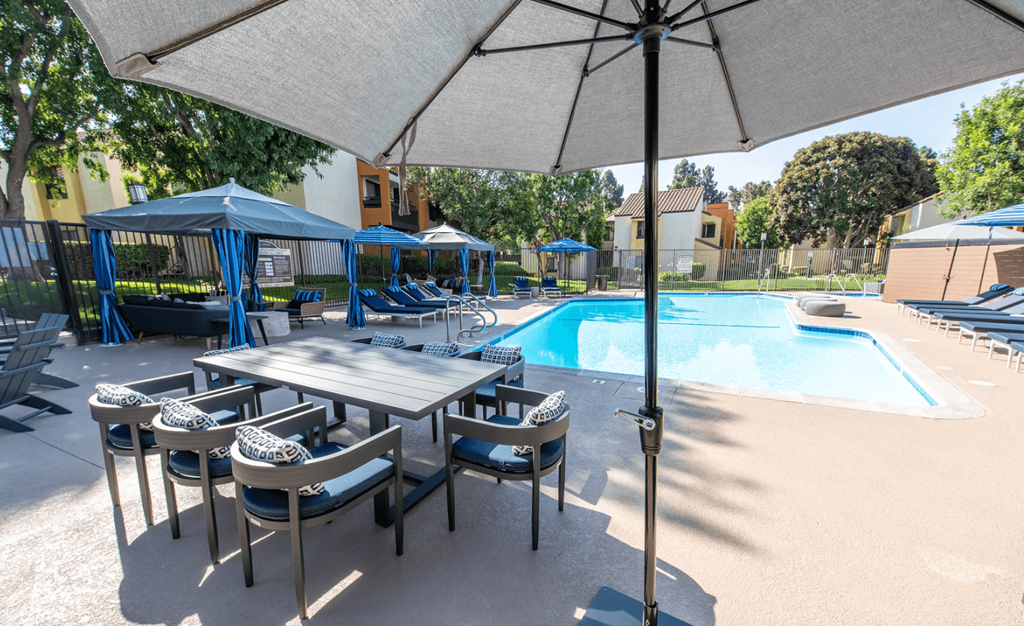 Pool view with dining furniture, cabanas, and sparkling pool