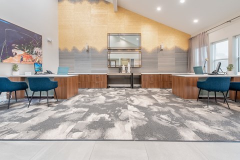 a communal area with two desks and chairs and a kitchen